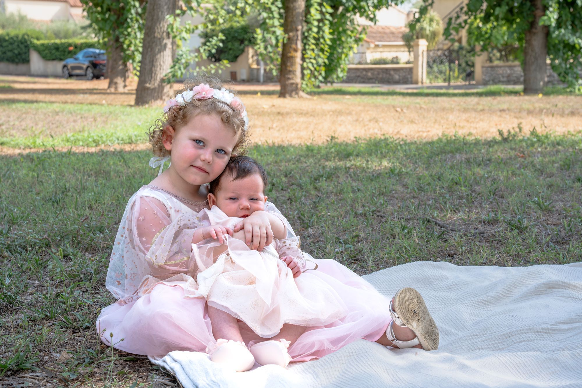 Fillette en robe de tulle rose tenant un nouveau-né dans l'herbe
