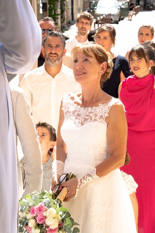 Mariée émue entourée de ses proches à l'entrée de l'église