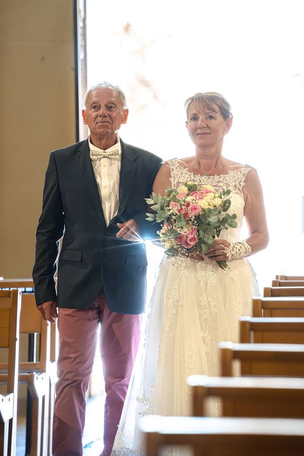 Entrée de la mariée accompagnée dans l'allée de l'église