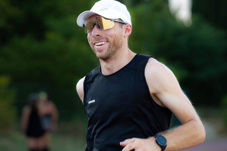 Coureur souriant en débardeur noir dans la lumière du soir