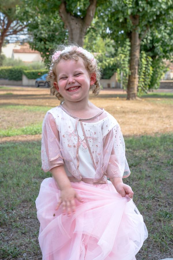 Fillette souriante en robe rose et couronne de fleurs