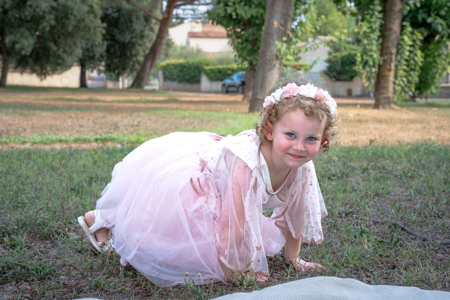 Fillette à quatre pattes dans l'herbe, sourire complice